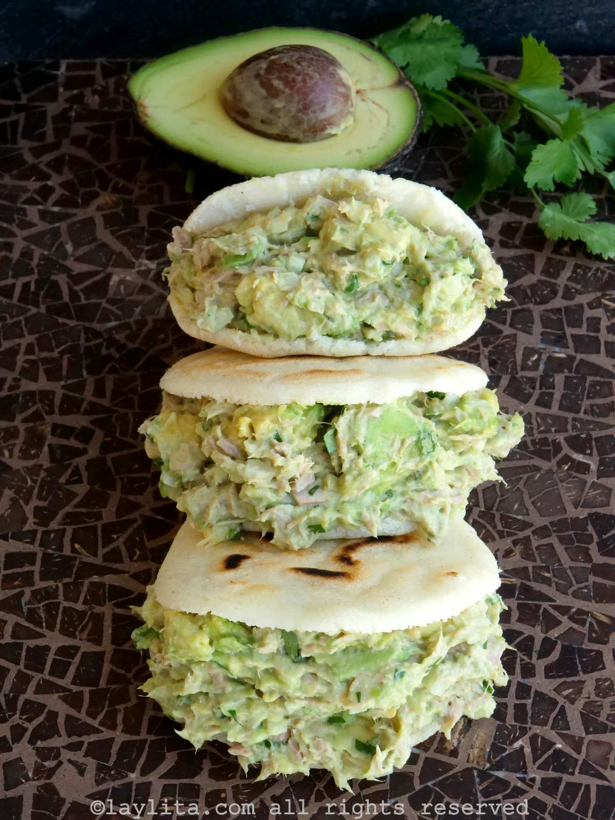 Vista superior de tres arepas rellenas de ensalada de atún en fila.