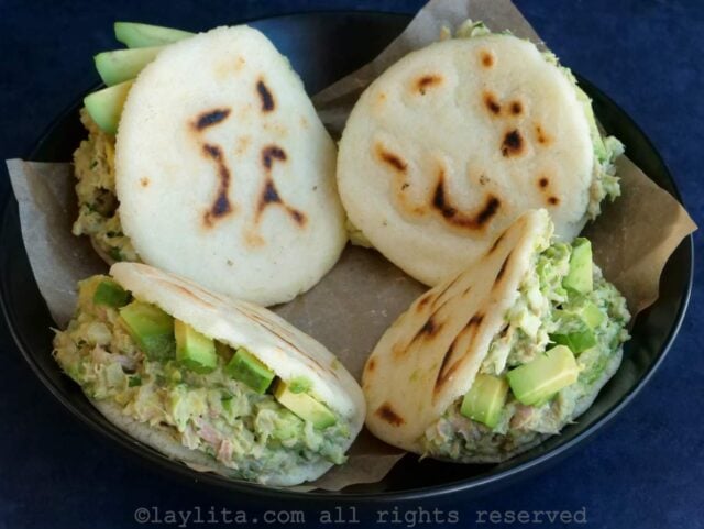 Cuatro arepas con relleno de ensalada y aguacate en un bol negro