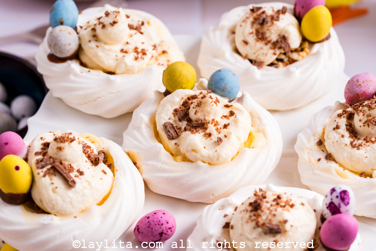 Varios merengues en forma de nido con relleno cremoso de limón y decorados con mini huevitos de chocolate