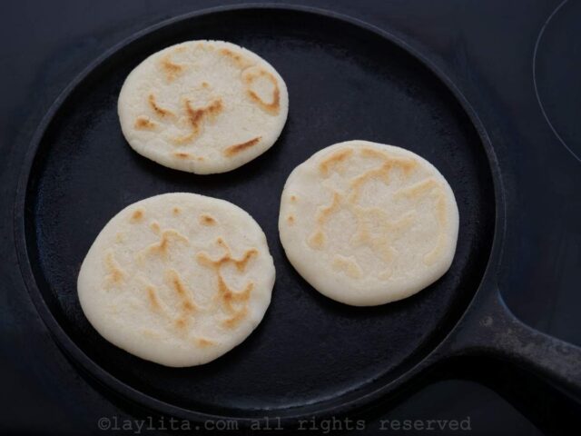 Tres arepas cocinandose en una plancha de cocina