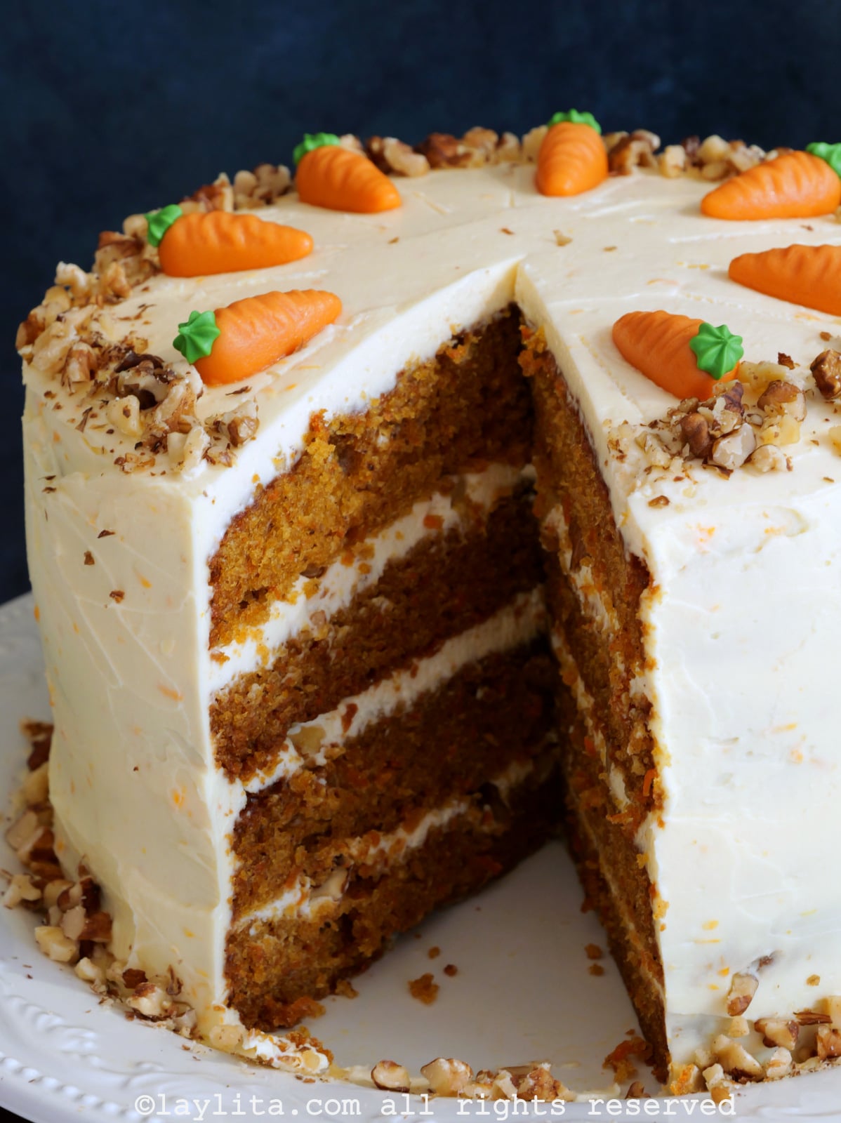 Primer plano de una torta de zanahoria con una rebanada quitada, mostrando las capas del pastel