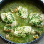 Pescado en salsa verde con almejas servido en una sartén