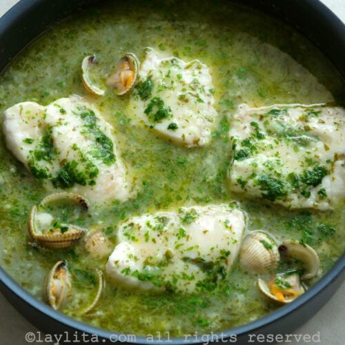 Pescado en salsa verde con almejas servido en una sartén