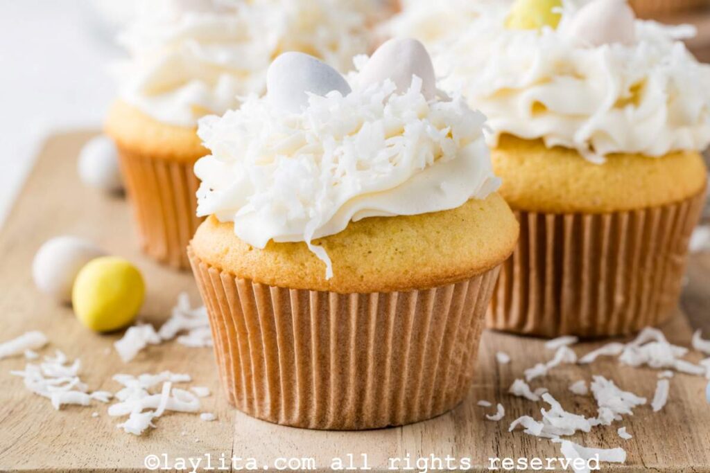
73
Un par de cupcakes de coco en una tabla con mini huevos de Pascua a un lado.