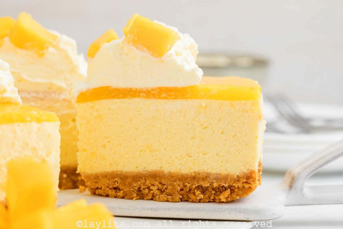 Una rebanada de cheesecake de mango en una espatula de metal