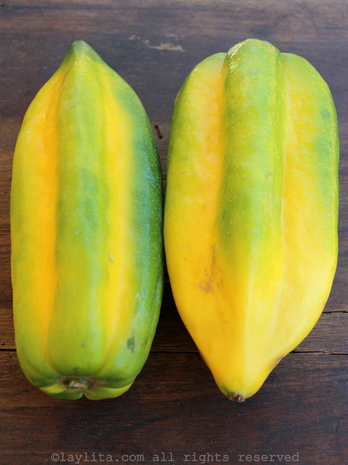 Dos babacos maduros pintones en una mesa de madera