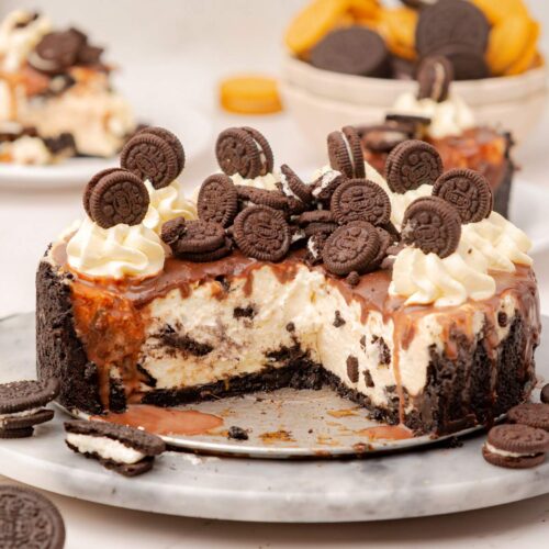 Un cheescake de galletas Oreo en una bandeja con algunas rebanadas faltantes para mostrar el interior.