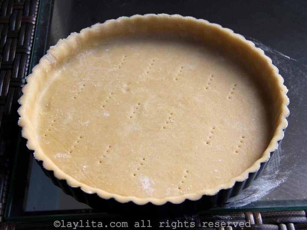 Un  molde de tarta con masa dulce antes de hornear en una mesa de vidrio