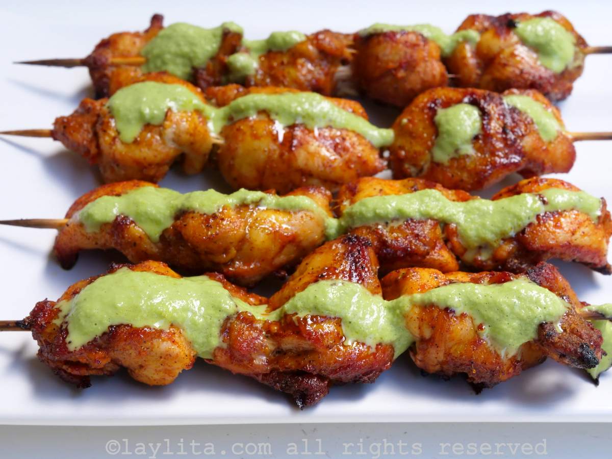 Primer plano de brochetas de pollo con salsa verde rociada por encima