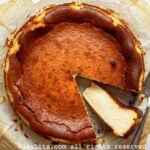 Una tarta de queso vasca encima de papel de hornear con una rebanada cortada