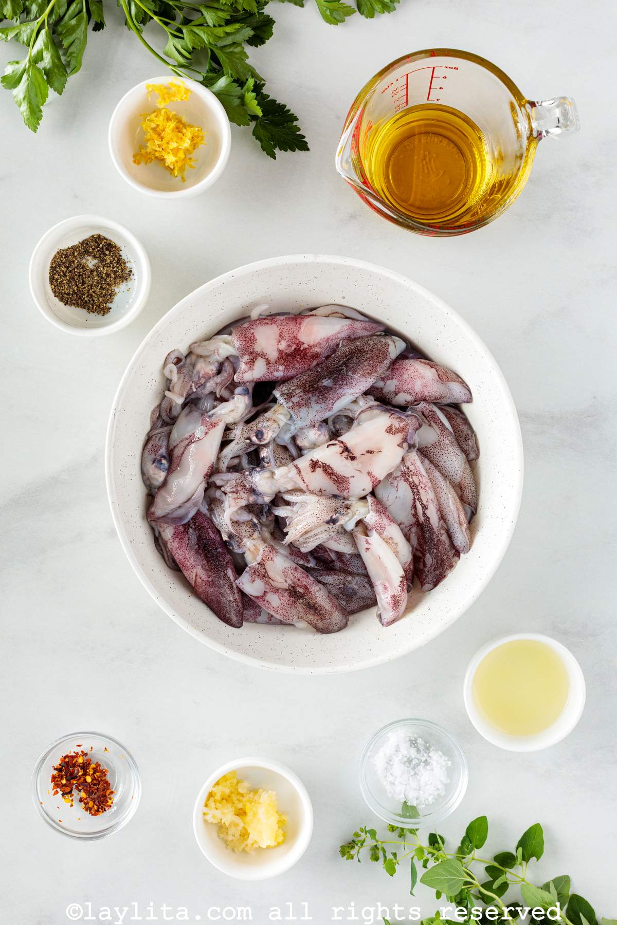 Ingredientes para preparar calamares asados a la parrilla con aderezo de limón y perejil en una encimera de cocina