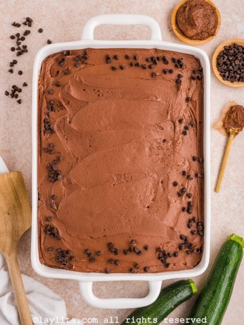 Un pastel de chocolate y zucchini decorado con betún cremoso de chocolate y chispas de chocolate