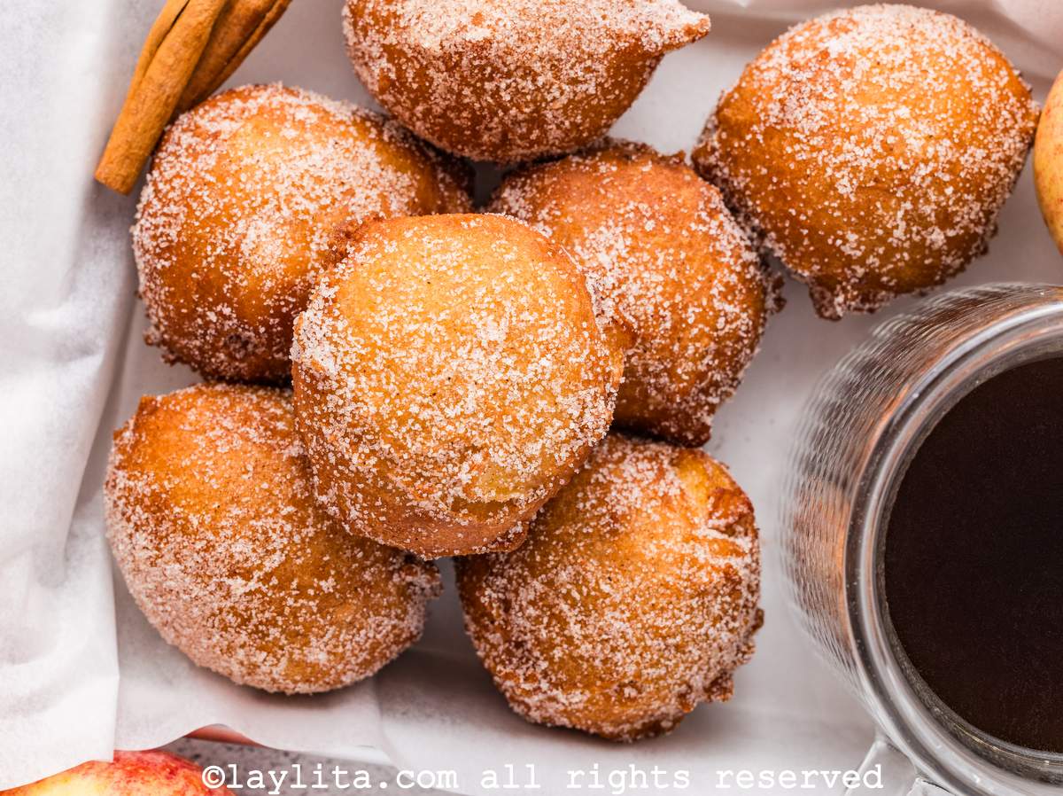 Vista superior de varios buñuelos dulces con azúcar encima y una salsa dulce en el fondo