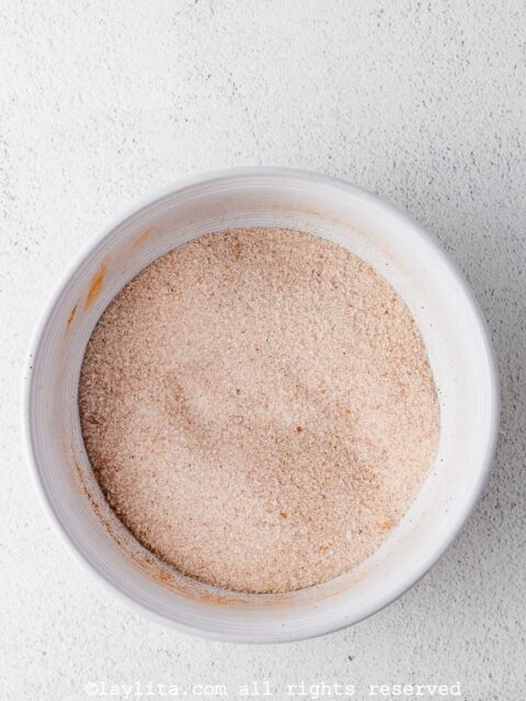 En un bol pequeño aparte, mezcla la ½ taza (100 gramos) de azúcar restante con 1 cucharadita de la canela molida (o las especias restantes).