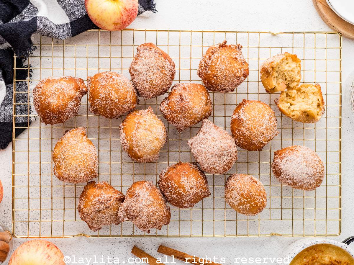 Vista superior de varios buñuelos de manzana encima de una rejilla de cocina