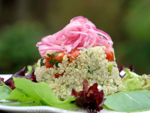 Salade de quinoa avec des tomates, des concombres, des oignons rouges, du jus de citron vert, de l’huile d’olive et de la coriandre, recouverte d’oignons rouges marinés
