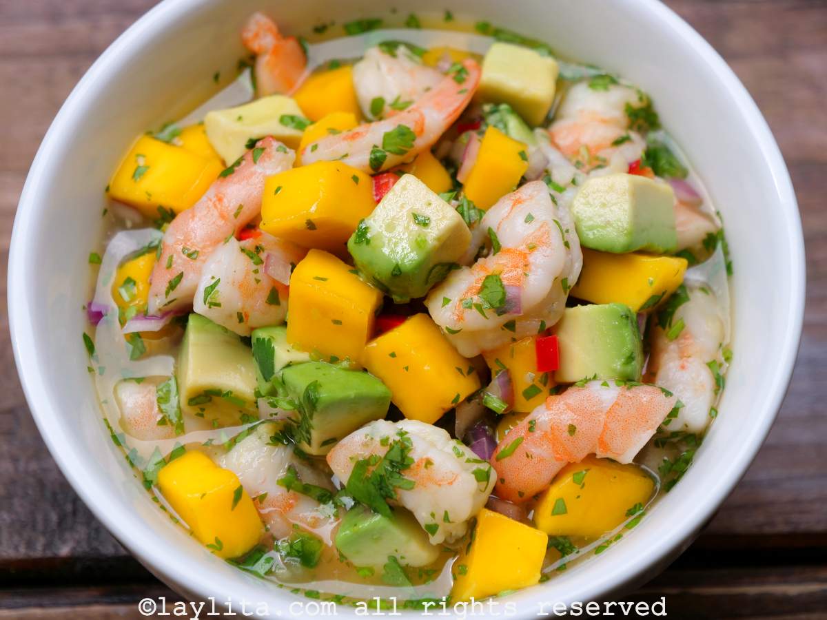 Ceviche de crevettes à la mangue et à l'avocat, servi dans un bol blanc sur une table en bois.