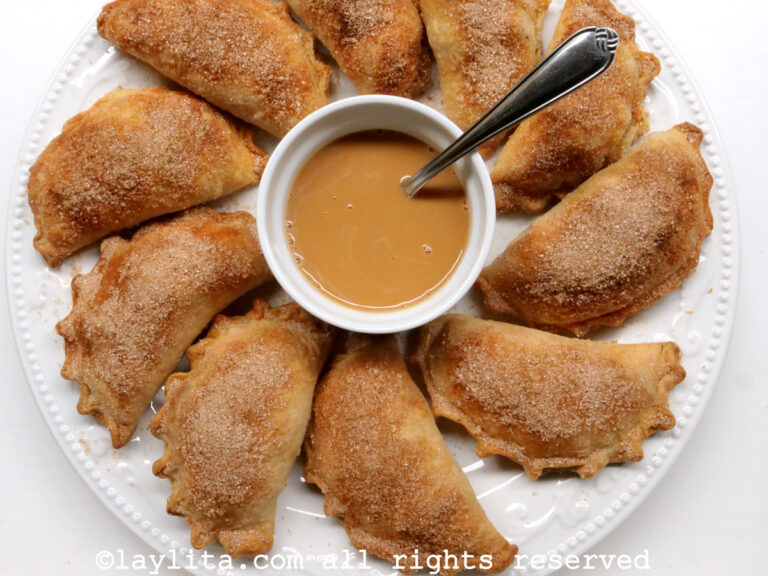Empanadas aux pommes et à la cannelle sur une assiette blanche, servies avec une sauce caramel au dulce de leche