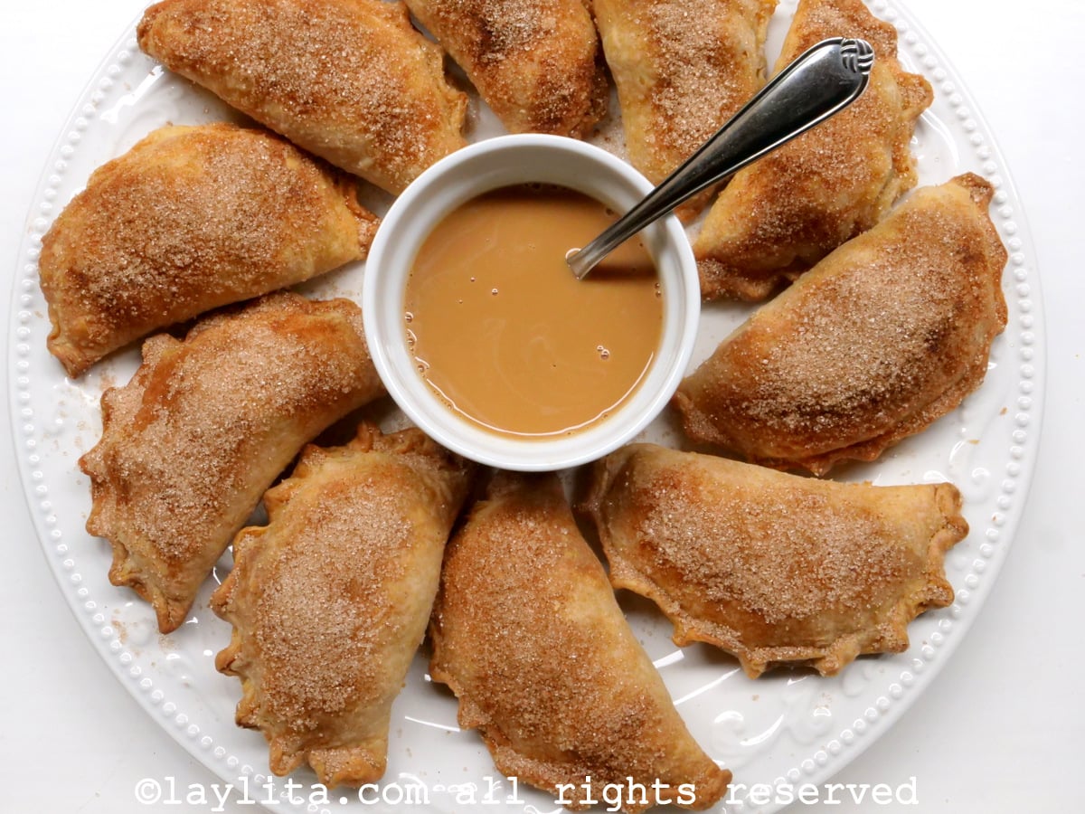 Empanadas aux pommes et à la cannelle sur une assiette blanche, servies avec une sauce caramel au dulce de leche