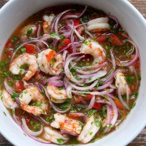 Traditional Ecuadorian shrimp ceviche made with poached shrimp, tomatoes, onions, lime juice, and cilantro in a white bowl