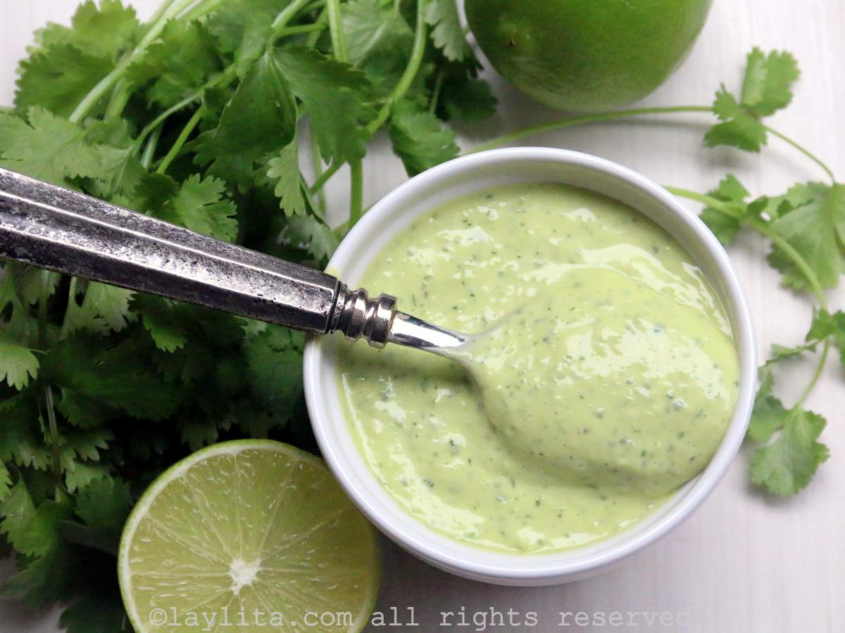 Homemade cilantro mayonnaise or coriander aoili - in a white ramekin with cilantro leaves and limes on the side