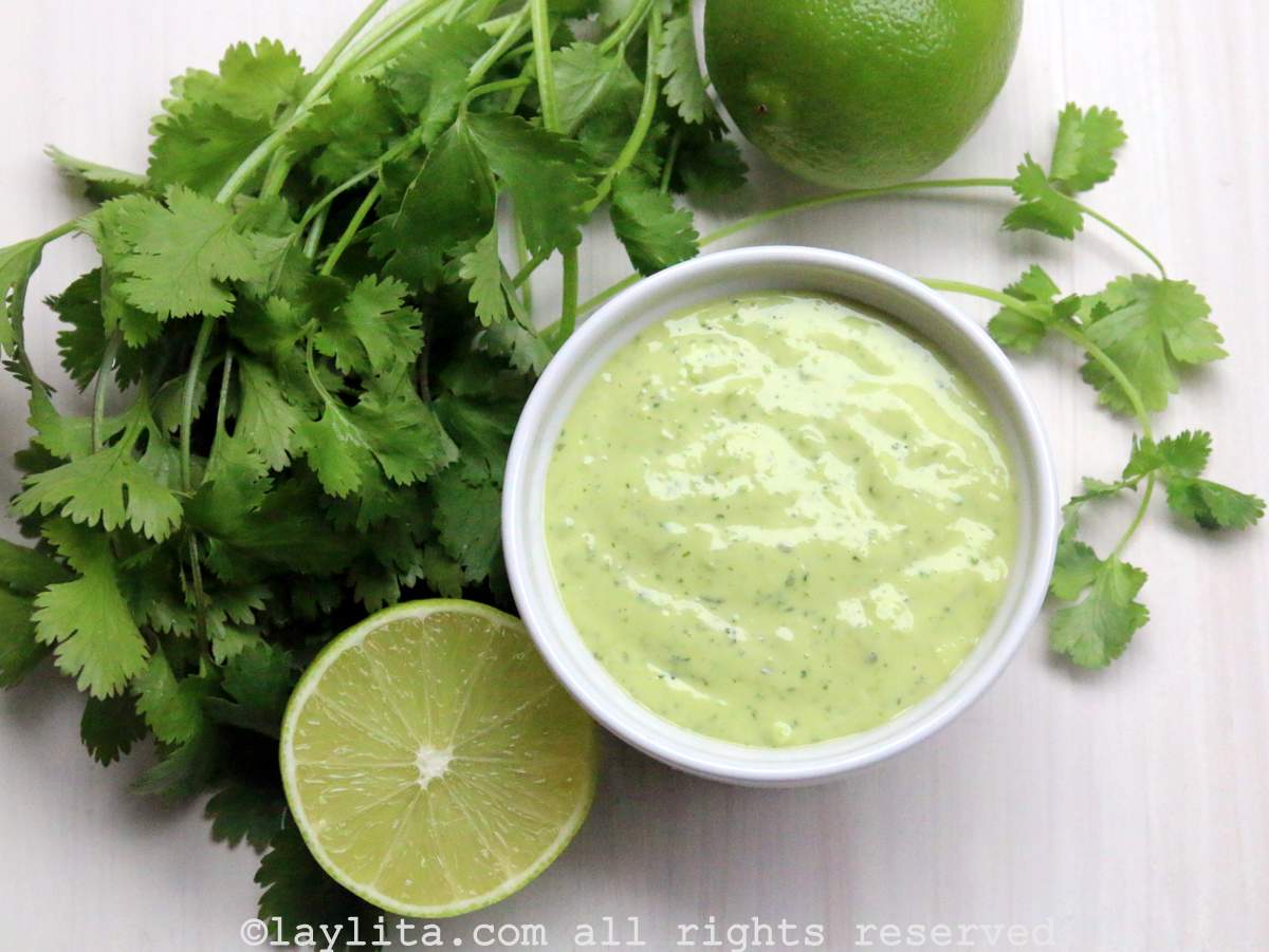 Homemade cilantro mayonnaise or aoili - in a white ramekin with cilantro leaves and limes on the side