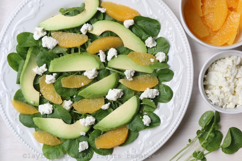 Layer the watercress leaves with the avocado slices, oranges, and goat cheese