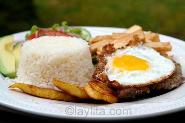 Assiette de churrasco équatorien : steak avec un œuf dur, riz, bananes plantain, frites et salade