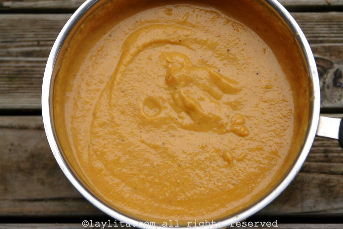 A pot full of ripe plantain purée on a wooden table