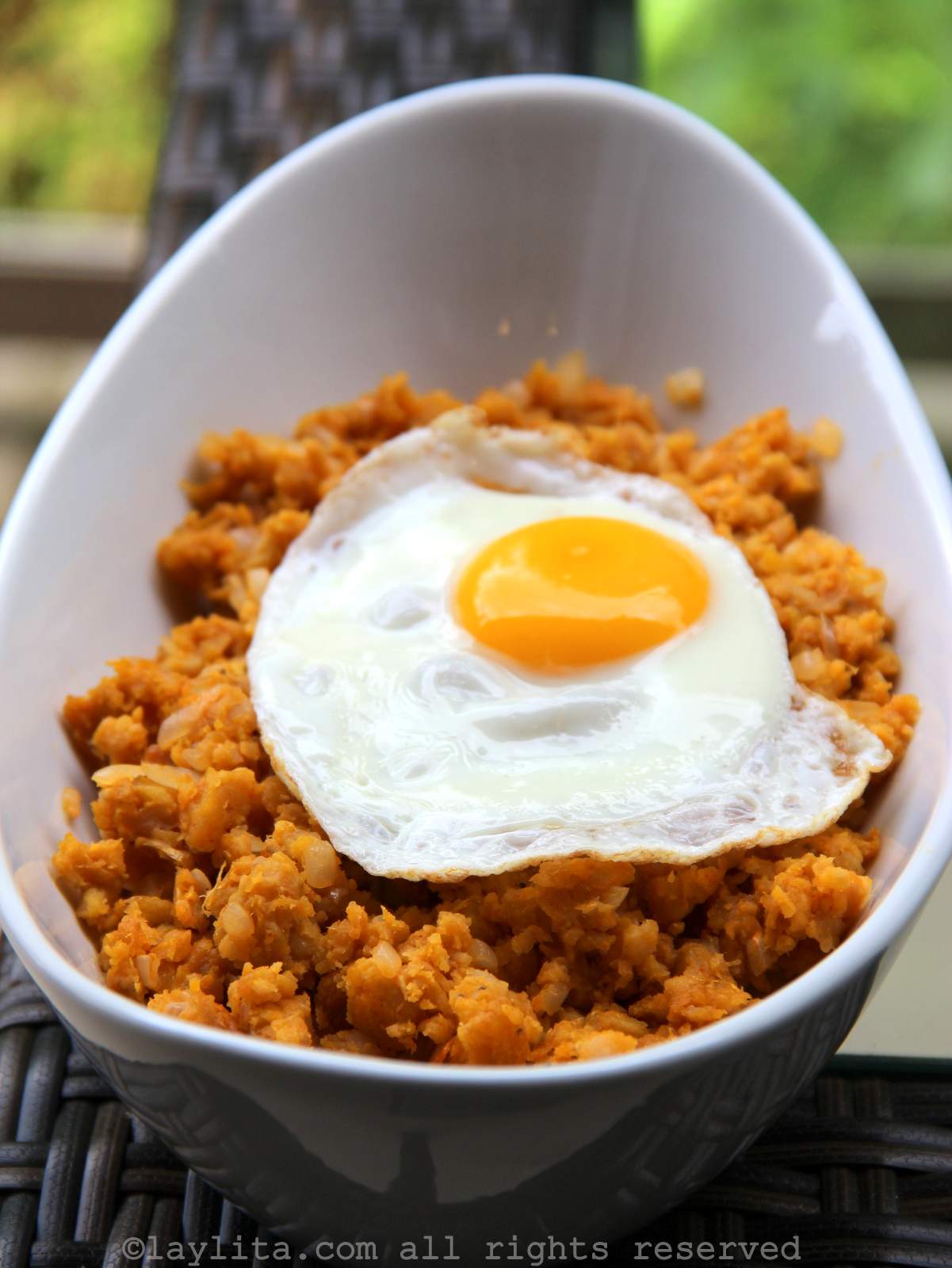 A white bowl with mashed green plantains and a fried egg