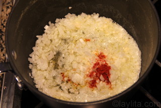 Faire revenir des oignons, de l'ail, du roucou et du sel dans du beurre.