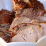 Closeup of Ecuadorian slow roasted pork slices in a white baking dish