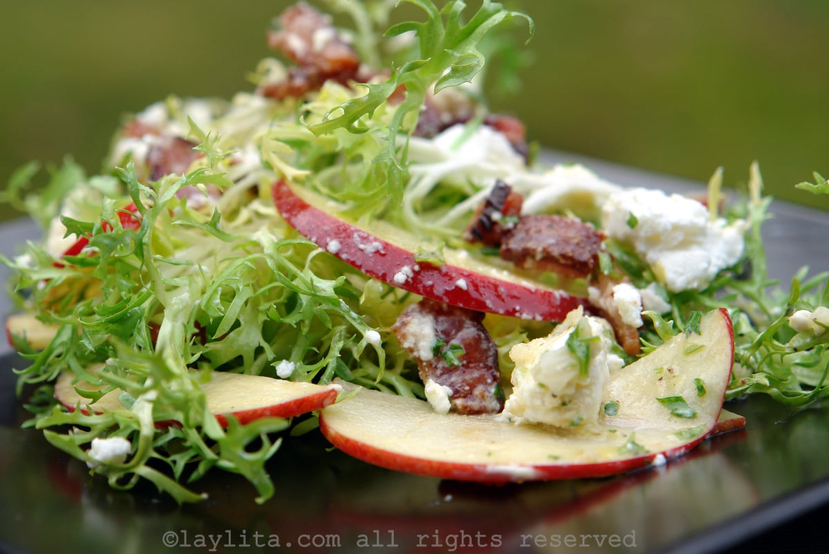 Frisée salad with apple, bacon and goat cheese on black plate