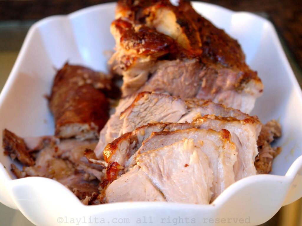 Ecuadorian pork hornado cut into slices in a white serving dish