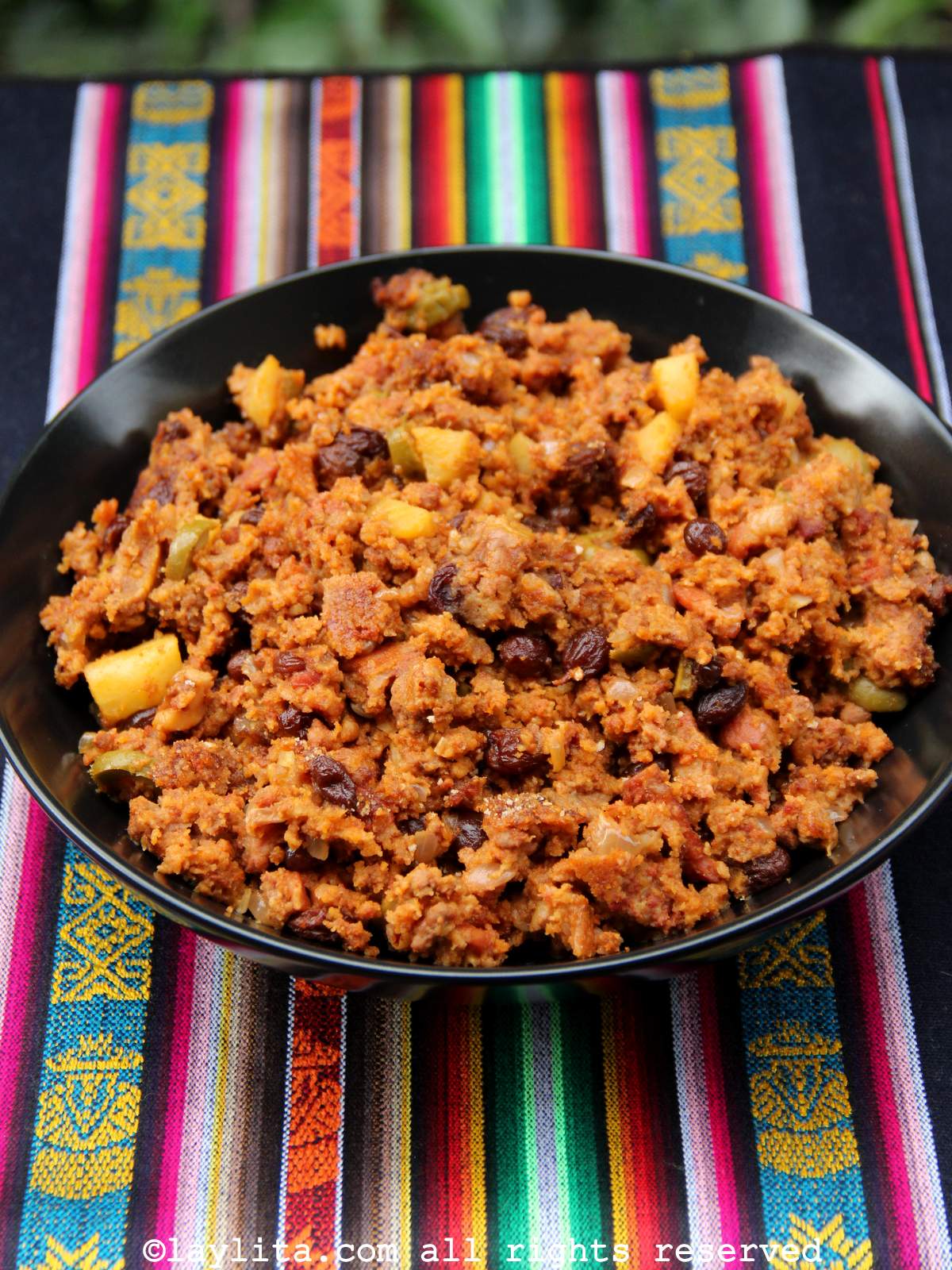 A black bowl full of Ecuadorian style turkey stuffing on a colorful tablecloth