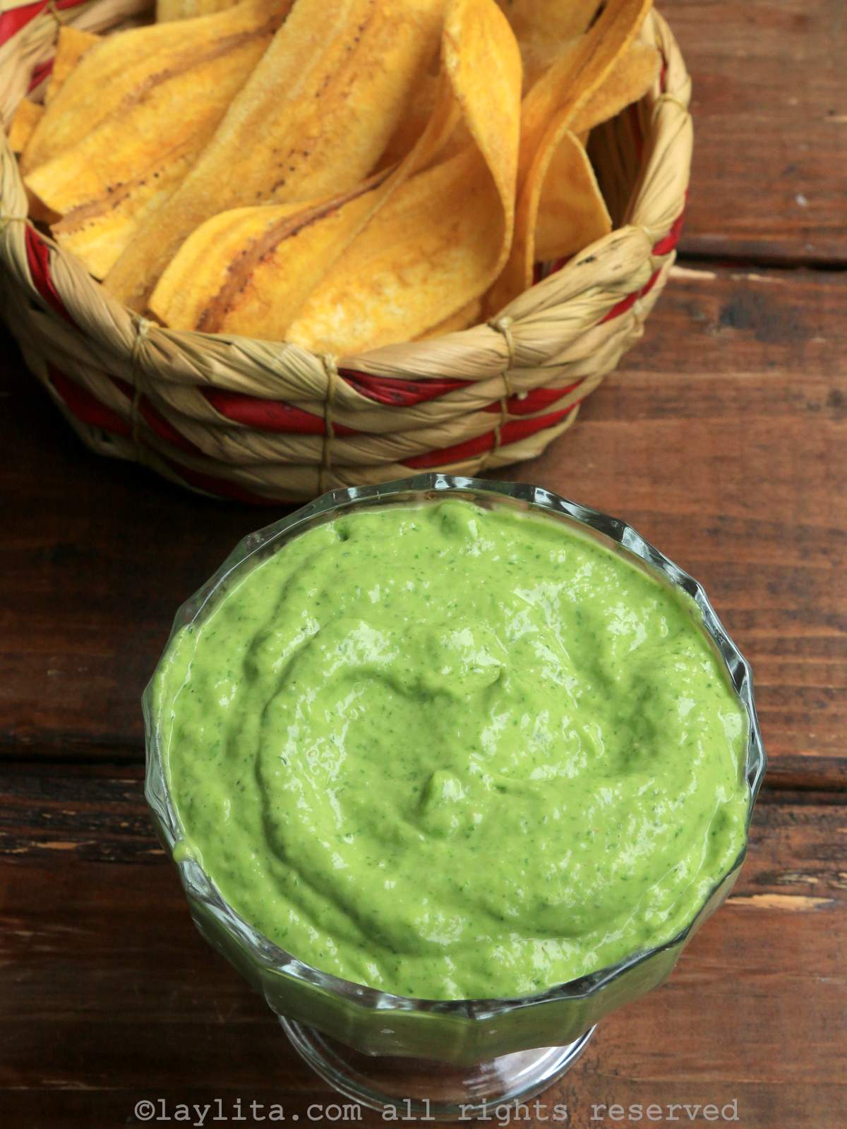Bowl of avocado salsa with plantain chips in the background