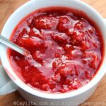 Homemade strawberry sauc in a white bowl, with a spoon in it