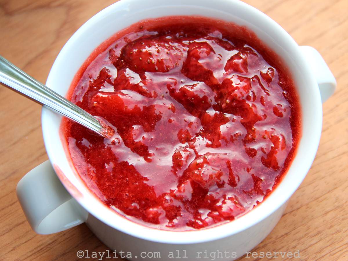 Homemade strawberry sauc in a white bowl, with a spoon in it
