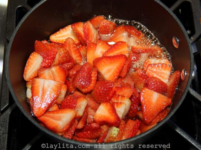 Sliced strawberries, sugar and lemon juice in a pot on the stove