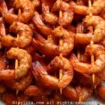Closeup of several grilled shrimp skewers on a white plate