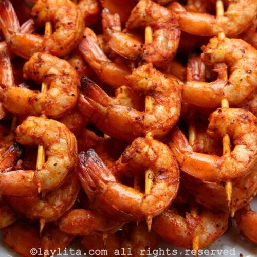 Closeup of several grilled shrimp skewers on a white plate