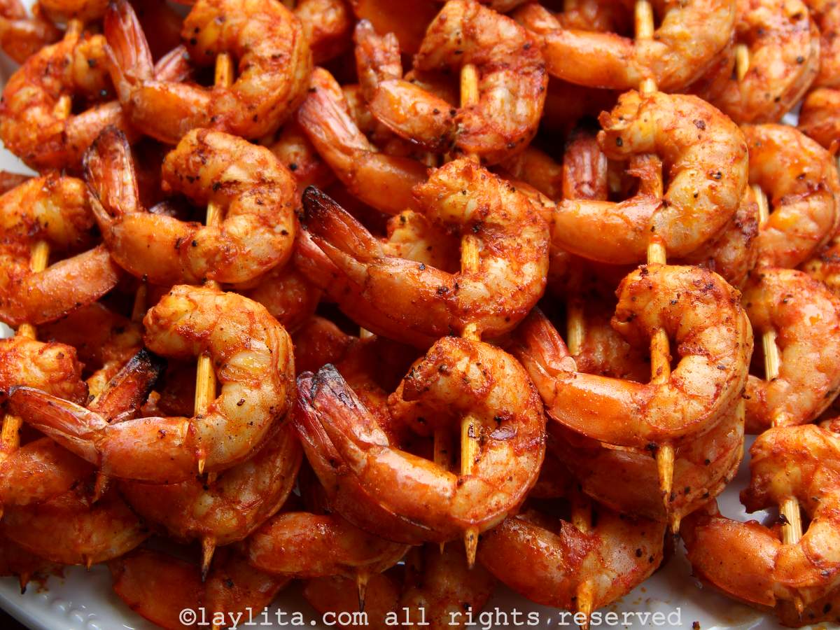 Closeup of several grilled shrimp skewers on a white plate