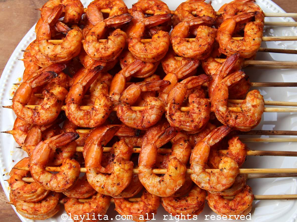 Closeup of several grilled shrimp skewers on a white plate