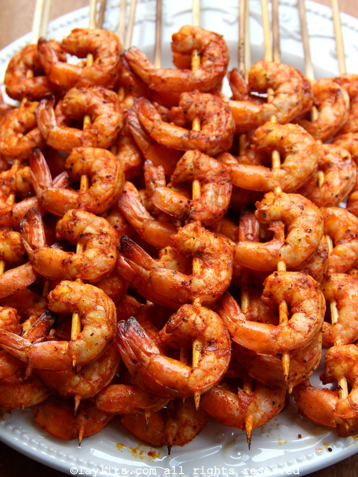 Overhead view of a white platter full of passion fruit marinated grilled shrimp pinchos or skewers