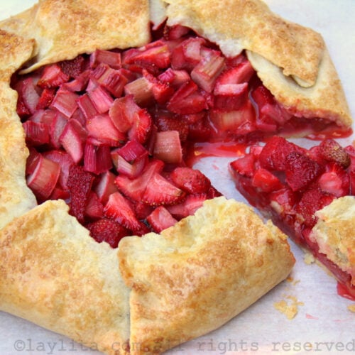 View of a rhubarb strawberry galette on a piece of parchment paper with a slice cut out of the galette