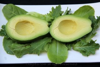 Place the peeled avocado halves on a plate with lettuce or greens underneath
