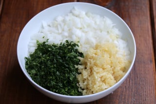 Diced onions, crushed garlic and chopped herbs for the refrito or sofrito
