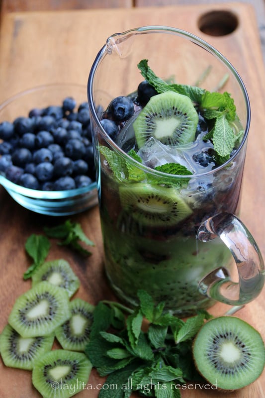 Add kiwi puree and rum, then add some ice, mint, kiwi slices, and repeat with the blueberry layer.