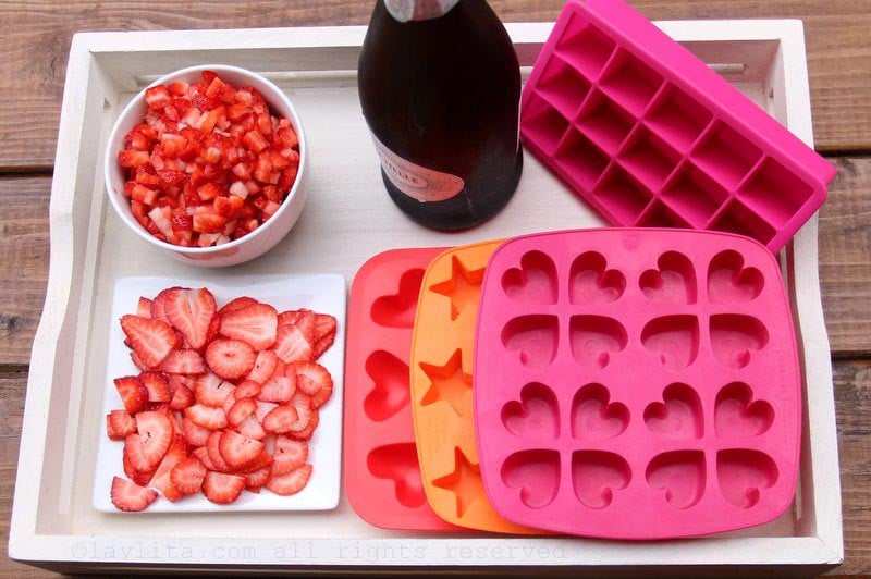 Ice cube trays, sliced and diced berries, and sparkling wine to make fun ice cubes