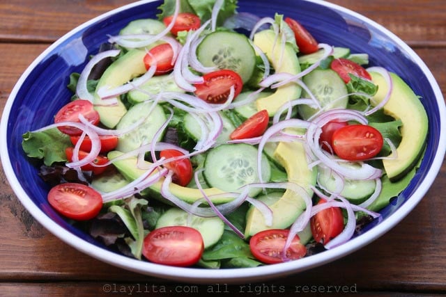 Ponga las hojas de lechuga en una ensaladera con las rodajas de aguacate, pepino, cebolla y tomates